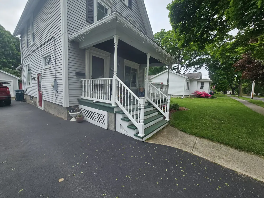 Front steps with a white railing leading up to a covered entry